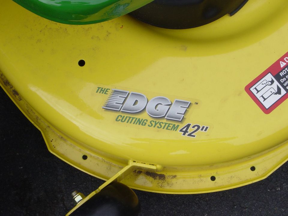 Yellow mower deck with "The Edge Cutting System 42"" decal and a red warning sticker