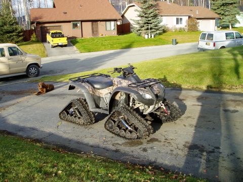 2000 Ford E350 - ATV equipped with tracks for snow or rough terrain is parked on a paved surface.