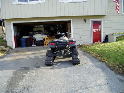 2000 Ford E350 - An all-terrain vehicle is parked in a driveway in front of a house and garage.