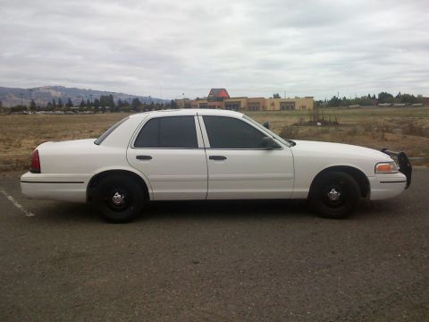 2000 Ford Crown Victoria - Side profile of a white 2000 Ford Crown Victoria sedan with tinted windows and black wheels.