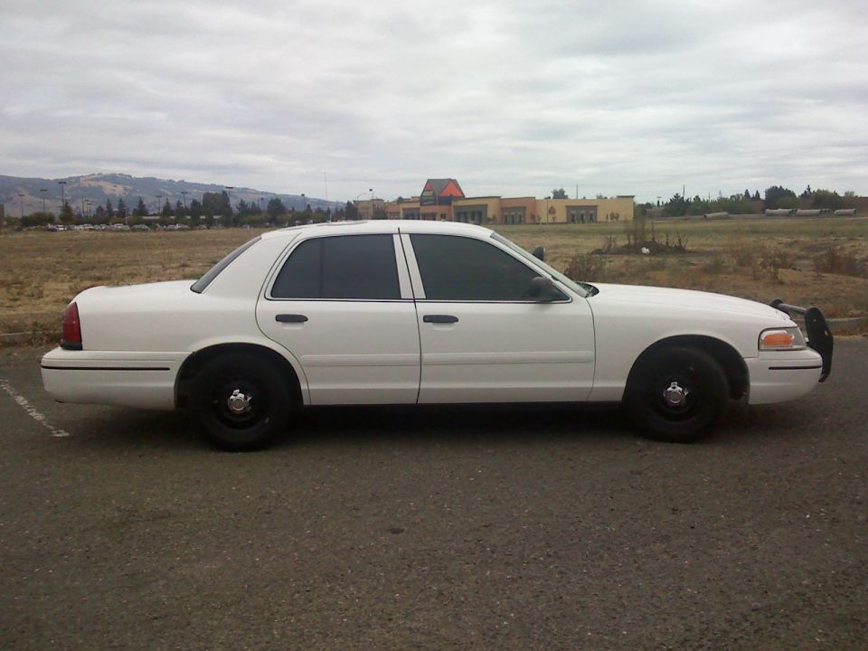 White 2000 Ford Crown Victoria sedan parked on asphalt, side view