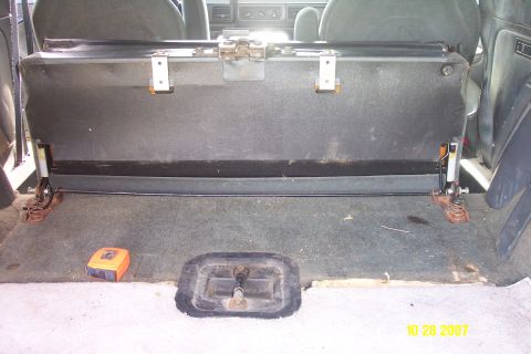 1992 Ford Bronco - The rear seat of a 1992 Ford Bronco is folded up, revealing the cargo area floor and mounting hardware.