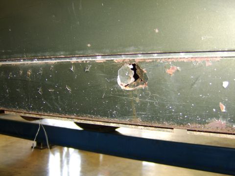 1976 Ford Bronco - Close-up of rust damage on the lower body panel of a vehicle.