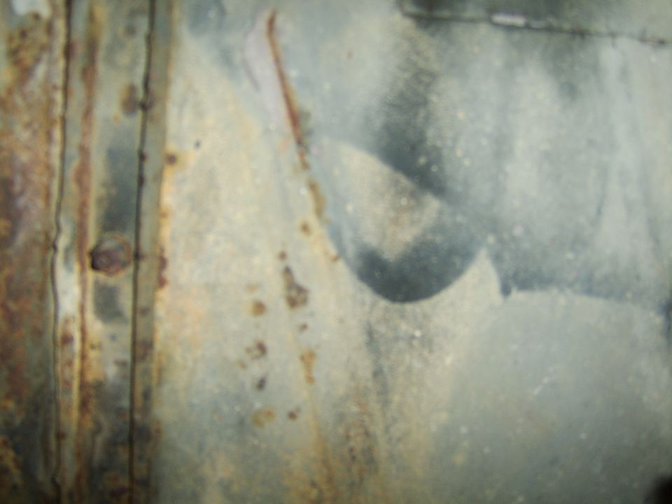 close-up of a rusty metal panel with some gray paint