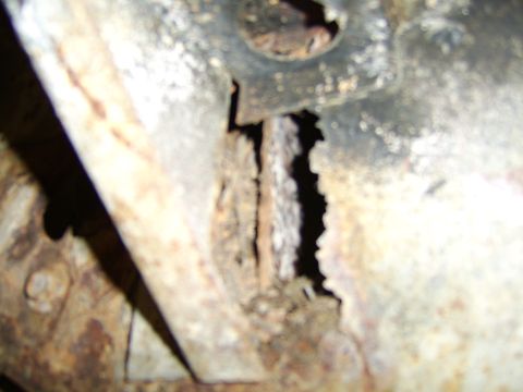 1976 Ford Bronco - Close-up of heavily rusted metal frame with visible holes and damage, indicating significant deterioration.