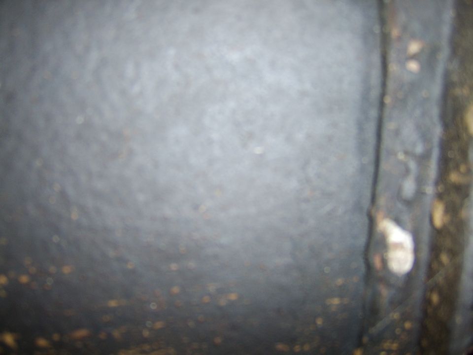 Close-up of textured metal surface with visible rust spots and a bolt