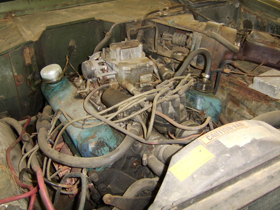 engine bay with carburetor, distributor, and fan shroud with caution label