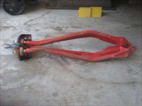 1996 Ford Bronco - Red suspension control arms with metal brackets and bolts are shown on a concrete floor.