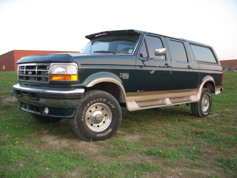 1995 Ford C-350 (Centurion Conversions) - This dark green SUV with tan trim is viewed from the front-three-quarter angle, showing a visor above the windshield.
