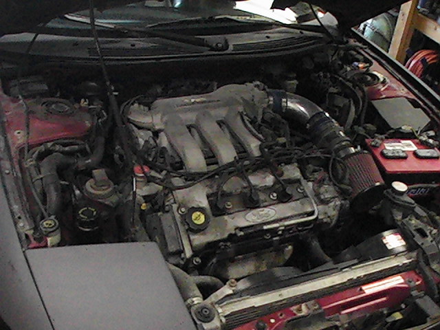Engine bay with V6 engine, red battery, and aftermarket air intake