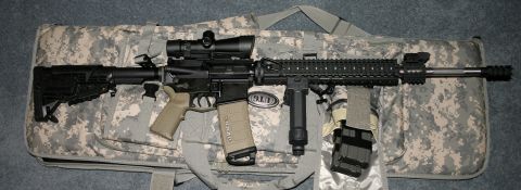 1994 Ford Bronco - An AR-15 rifle with accessories is displayed on a camouflage bag, with a SuperMotors watermark visible.