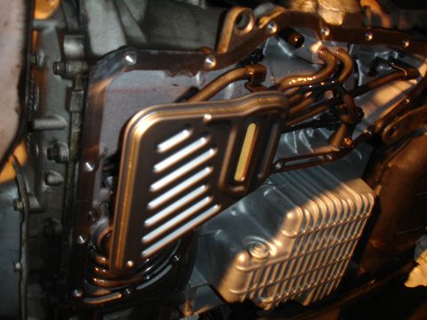 1993 Ford Taurus - Close-up view of a transmission oil filter and pan assembly, showing metal tubes and a ribbed pan.
