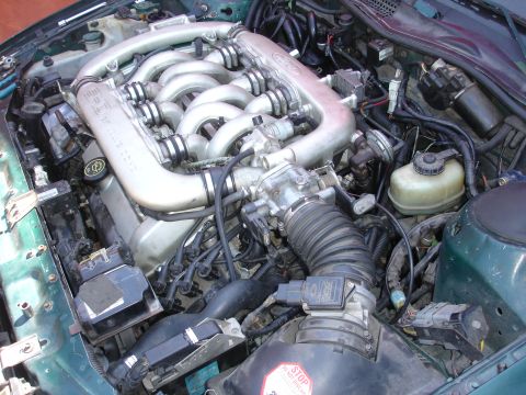 1993 Ford Taurus - Engine bay of a 1993 Ford Taurus, showing the V-shaped intake manifold and associated components.