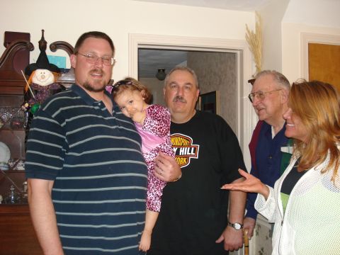 2000 Ford Crown Victoria - A group of people are gathered indoors, with one man holding a young child.