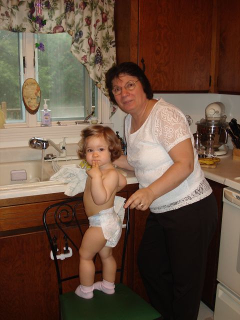 2000 Ford Crown Victoria - A woman and a baby are in a kitchen, with a sink and cabinets visible.
