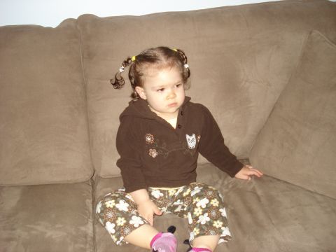2000 Ford Crown Victoria - A young child with braided pigtails sits on a plush sofa, looking off to the side.