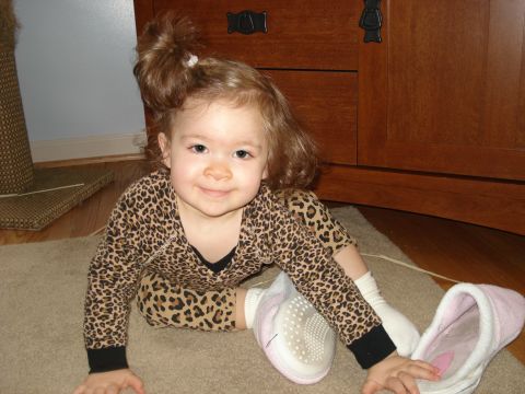2000 Ford Crown Victoria - A young child wearing pajamas and slippers is sitting on a carpeted floor near a wooden cabinet.