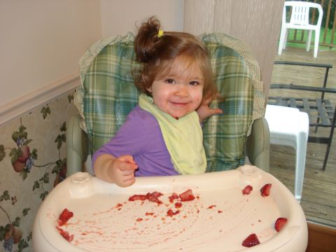 2000 Ford Crown Victoria - A toddler with a messy face and bib enjoys strawberries at a high chair.