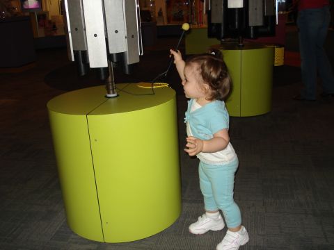 2000 Ford Crown Victoria - A young child engages with a musical exhibit at a museum, reaching up to strike a chime.
