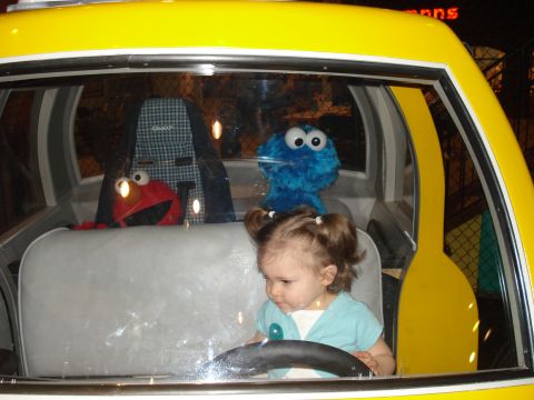 2000 Ford Crown Victoria - A young child sits behind the wheel of a toy taxi, accompanied by Elmo and Cookie Monster plush toys.