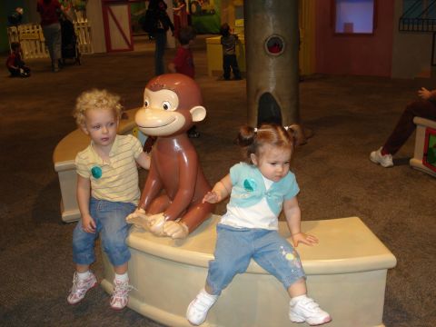 2000 Ford Crown Victoria - Two young children pose with a statue of the beloved character Curious George in an indoor exhibit.