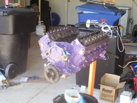 1991 Ford Bronco - A purple engine is mounted on an orange stand in a garage setting, with various tools and containers nearby.