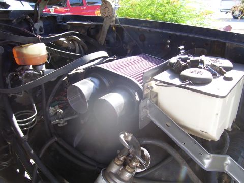 1991 Ford Bronco - Engine bay with aftermarket air intake and fluid reservoir; red vehicle in background.