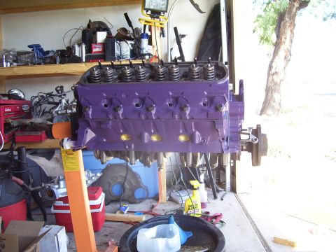 1991 Ford Bronco - A purple V8 engine block is mounted on an engine stand in a garage setting.