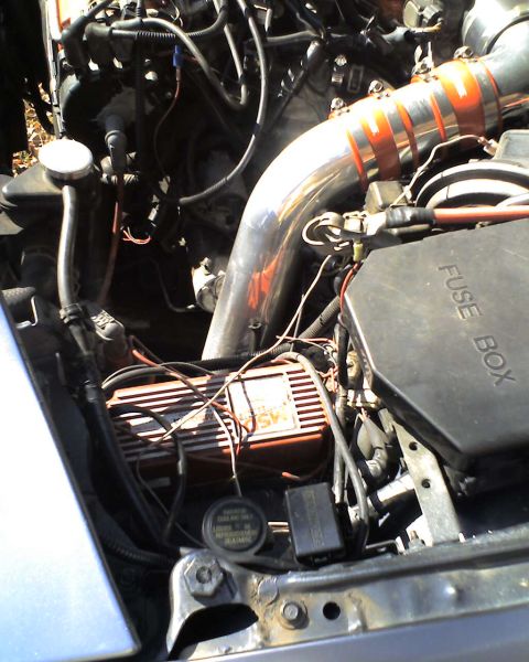 1994 Ford Probe - Close-up of an engine bay a custom chrome intake pipe with orange hose clamps and a visible fuse box.