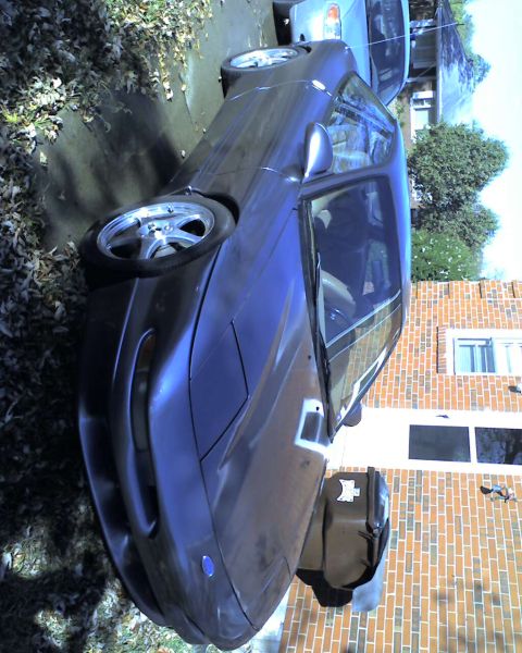 1994 Ford Probe - A dark blue 1994 Ford Probe is parked next to another vehicle in a driveway.