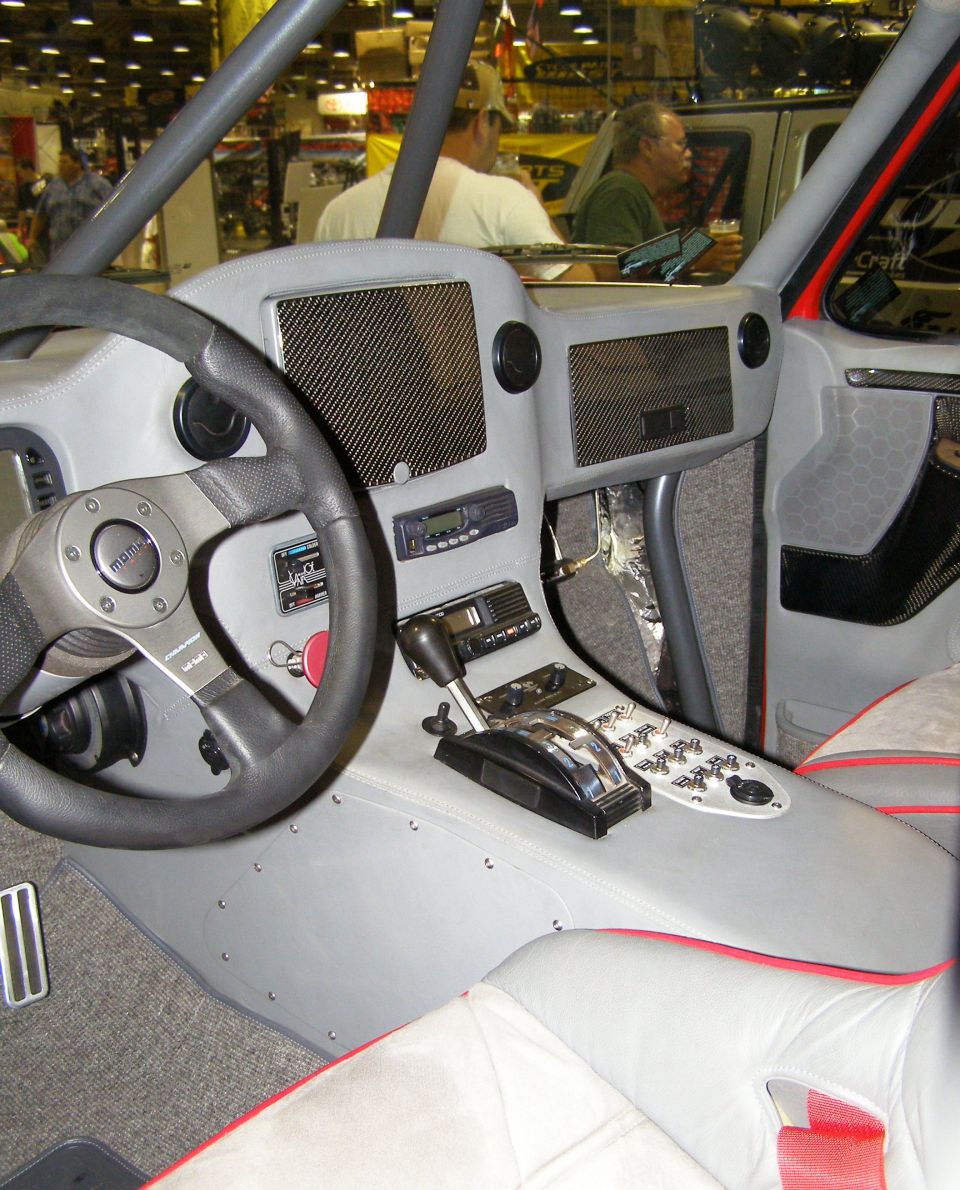 Custom gray interior with Momo steering wheel, carbon fiber dash panels, and switch-filled center console at a car show