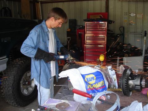 1996 Ford F-150 - A differential gear is visible on a workbench, with a NAPA Auto Parts bag nearby and sparks flying from grinding.