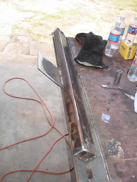 1996 Ford F-150 - A fabricated metal component, possibly a custom part, rests on a workbench with tools and supplies nearby.