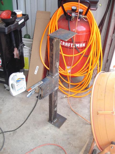 1996 Ford F-150 - A metal fabrication stand is shown with a clamp attached, beside an air compressor and coiled hose.