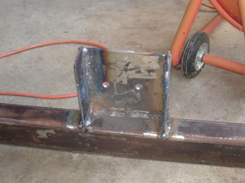 1996 Ford F-150 - A custom metal bracket is welded onto a vehicle frame, showing signs of recent work and some rust.