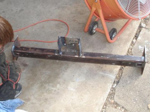 1996 Ford F-150 - A fabricated metal crossmember is shown on a concrete surface, with a person and a fan nearby.