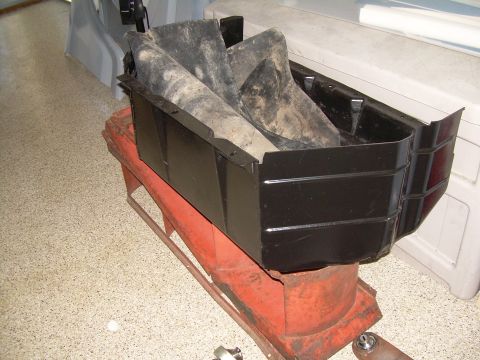 1986 Ford Bronco - Black skid plate with rubber flaps is shown mounted on a red stand, likely for repair or storage.