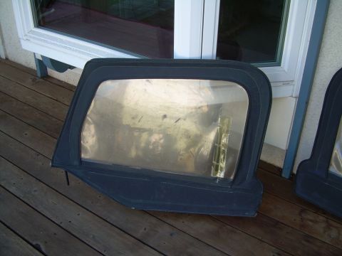 1986 Ford Bronco - A black soft top window frame with a clear plastic window is displayed on a wooden deck.