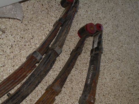 1986 Ford Bronco - Close-up of rusty leaf springs with red bushings and a visible part number.