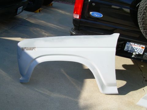 1986 Ford Bronco - A white fender part is shown in front of a black Ford Bronco with a California license plate.