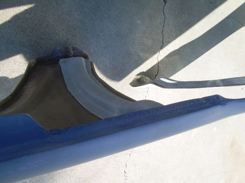 1986 Ford Bronco - A close-up view of a blue and gray car fender part resting on a cracked concrete surface.