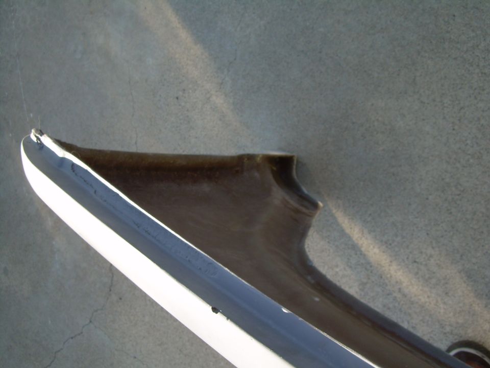 Close-up of a white and dark brown automotive fender part against a gray background