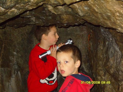 1989 Ford Bronco - Two young boys venture into a cave, one holding a flashlight to illuminate their surroundings.