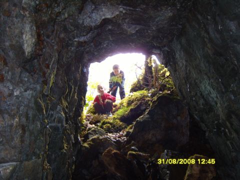 1989 Ford Bronco - Two children explore the entrance of a mossy cave, with daylight shining through.