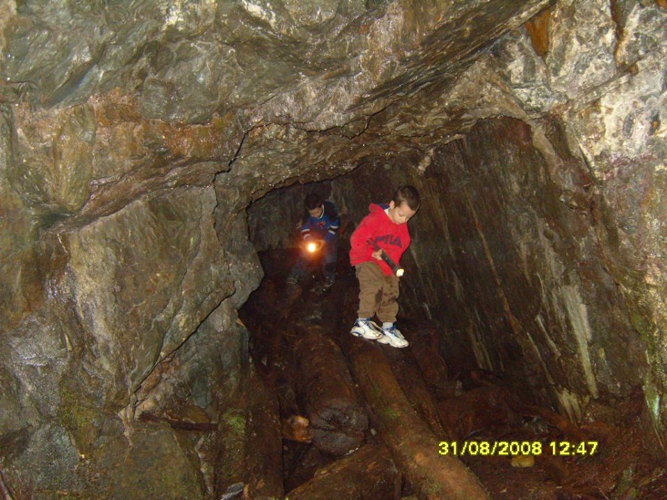 Two kids with flashlights walk through a rocky cave