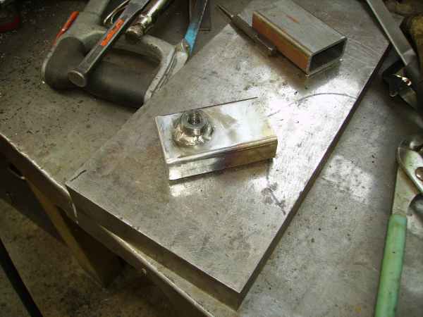 Metal bracket with nut and bolt on workbench with tools