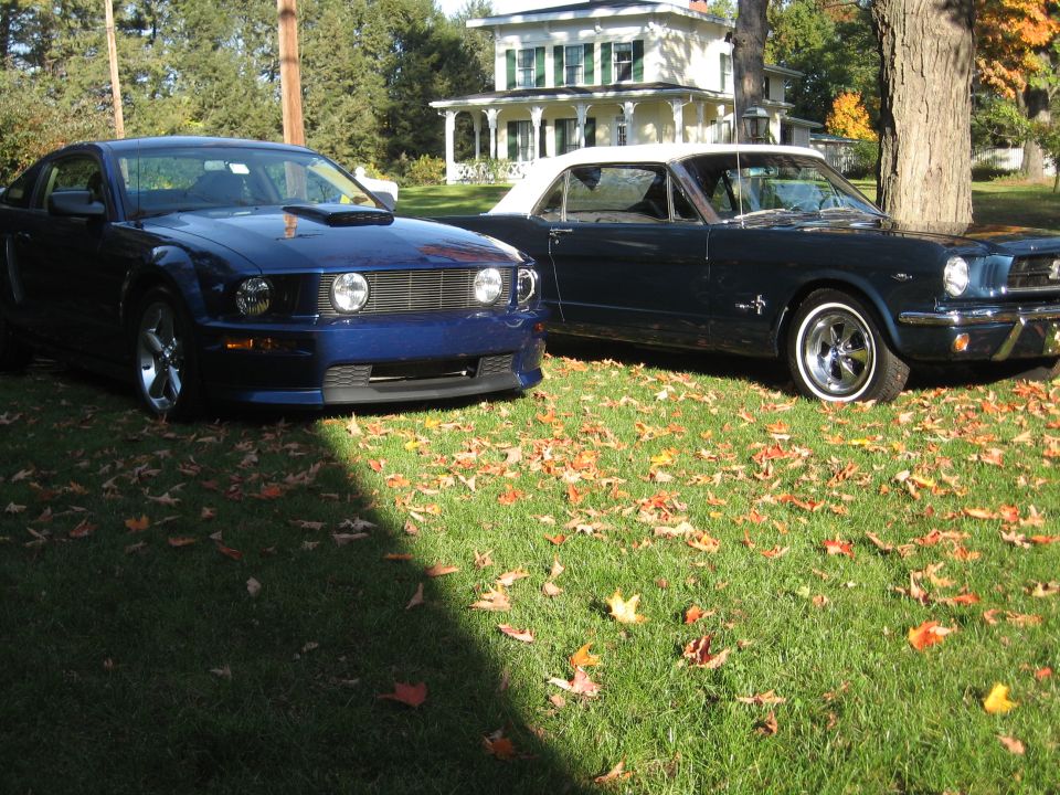 Dark blue classic Mustang convertible next to a modern blue Mustang coupe