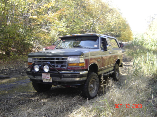 1994 Ford Bronco in a wooded area, front view with brush guard and lights