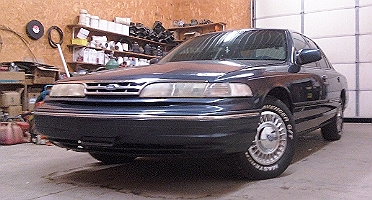 1997 Ford Crown Victoria - A dark blue 1997 Ford Crown Victoria is parked in a garage, viewed from the front right.