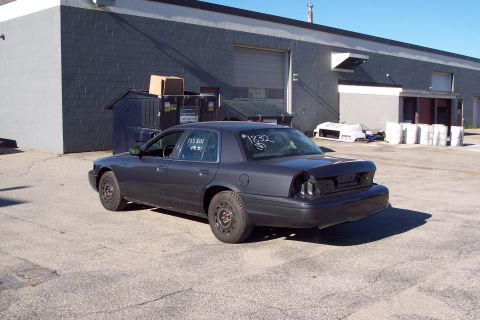 2001 Ford Crown Victoria - A dark gray 2001 Ford Crown Victoria is parked in an industrial lot with visible markings on the windows.